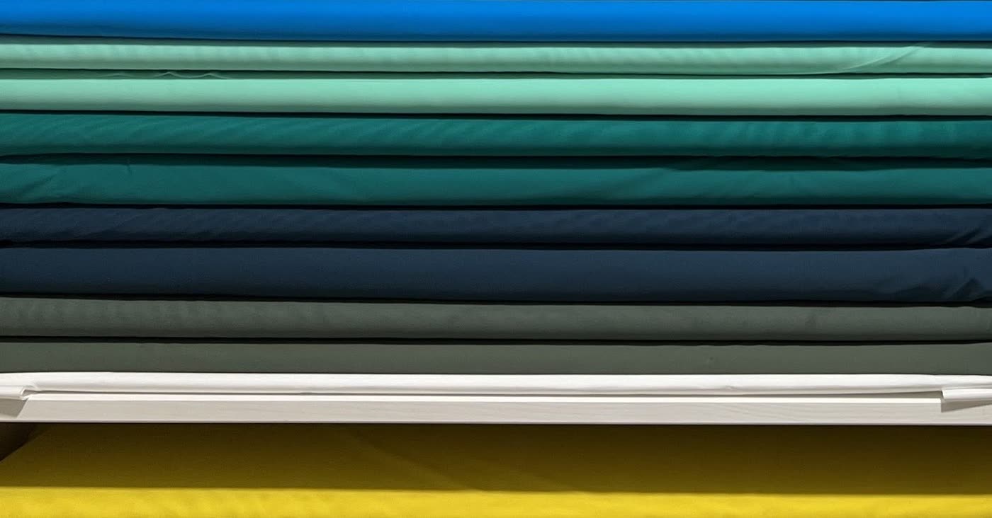 Bolts of stretch costume fabric stacked by colour on the studio shelves