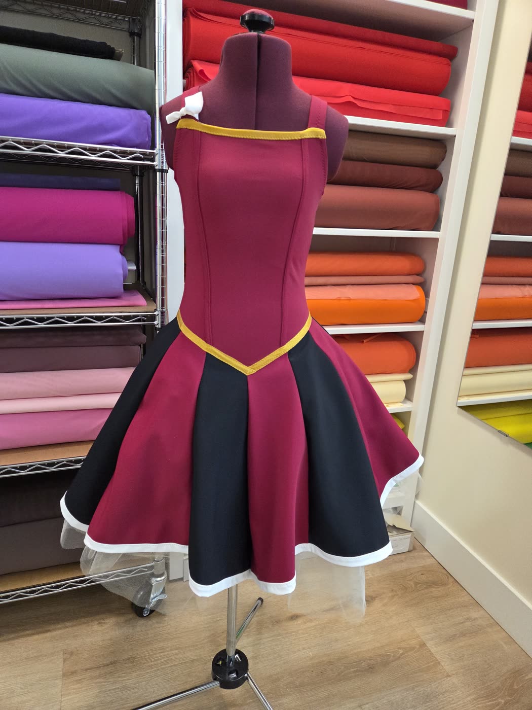 Burgundy and black competition dress on a dress form in the fabric room