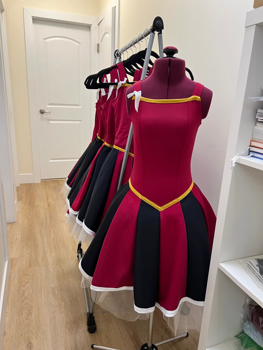 Matching burgundy and black competition dresses on forms and hangers